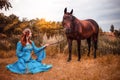 Beautiful young female elf with long dark wavy hair petting her horse resting in the woods forest nymph stroking her horse care Royalty Free Stock Photo