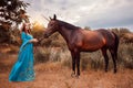 Beautiful young female elf with long dark wavy hair petting her horse resting in the woods forest nymph stroking her horse care Royalty Free Stock Photo