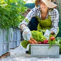 Beautiful young female farmer with freshly harvested vegetables in her garden. Homegrown bio produce concept.
