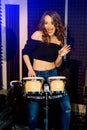 Beautiful young female feels happy while playing drum in the studio background Royalty Free Stock Photo