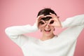 Beautiful young female model posing at studio over pink background wearing white sweater and makes faces. Royalty Free Stock Photo