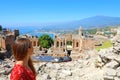 Beautiful young female model in the ruins of the ancient Greek theater in Taormina with the Etna volcano and Ionian sea on the Royalty Free Stock Photo