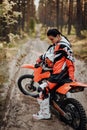 Beautiful young female racer riding motocross bike on a trail of sand in the woods Royalty Free Stock Photo