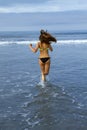 Beautiful young female runs into the ocean surf Royalty Free Stock Photo