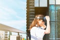 Beautiful young female in white t-shirt putting on virtual reality headset. Modern glass business building facade in the