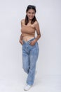 A beautiful young FIlipino woman smiling while her hands inside her jeans, moving forward. Full body photo, isolated on a white Royalty Free Stock Photo