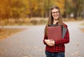 Beautiful young financial businesswoman in glasses looking at camera and smiling while standing in park after business meeting Royalty Free Stock Photo