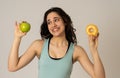 Attractive young woman on a diet deciding between an apple and a doughnut Royalty Free Stock Photo