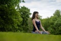 Beautiful young fit woman meditating, breathing, sitting with crossed legs in Lotus Posture in the park on summer day. Royalty Free Stock Photo