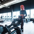 beautiful young fitness woman in black sportswear working out and exercising by machine in the gym Royalty Free Stock Photo