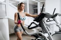 Beautiful young fitness woman at the gym exercising on the xtrainer machines. Attractive fit model doing cardio. Fat