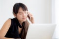 Beautiful young freelance asian woman smiling working on laptop computer and talking mobile smart phone at desk Royalty Free Stock Photo