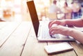 beautiful young freelance woman`s hands busy working on her laptop sitting at wooden table in a coffee shop Royalty Free Stock Photo