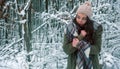 Beautiful young freezing girl portrait with scarf, knitted hat, rubbing her cold hands in snowy christmas winter forest Royalty Free Stock Photo