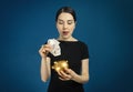 Beautiful young funny woman puts Russian money rubles in a gold piggy bank