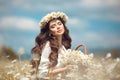 Beautiful young girl with basket of flowers over chamomile field. Carefree happy brunette woman with healthy wavy hair having fun Royalty Free Stock Photo