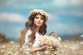 Beautiful young girl with basket of flowers over chamomile field. Carefree happy brunette woman with healthy wavy hair having fun Royalty Free Stock Photo