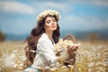 Beautiful young girl with basket of flowers over chamomile field. Carefree happy brunette woman with healthy wavy hair having fun Royalty Free Stock Photo