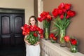 A beautiful young girl in a bathrobe holds in her hands a lot of red tulips in a vase. March 8 concept. Royalty Free Stock Photo