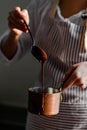 Beautiful young girl in beige apron is preparing delicious organic hot chocolate in old vintage ladle. Soft daylight, lifestyle Royalty Free Stock Photo