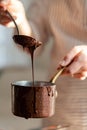 Beautiful young girl in beige apron is preparing delicious organic hot chocolate in old vintage ladle. Soft daylight, lifestyle Royalty Free Stock Photo