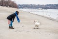 Beautiful young girl in the black coat feeding the swan on the beach near river or lake water in the cold winter weather, animal f Royalty Free Stock Photo