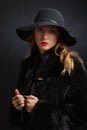 The beautiful young girl in a black hat with wide fields and fur coat Royalty Free Stock Photo