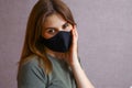 beautiful young girl in a black mask holds her hand over her face. Fabric mask for protection against coronavirus, covid-19 Royalty Free Stock Photo