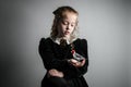 Beautiful young girl in black 1890s English Victorian 18th century child period dress holding a small wild bird