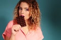 Beautiful young girl with blond hair and evening makeup eating chocolate Royalty Free Stock Photo