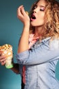 Beautiful young girl with blond hair and evening makeup eating popcorn Royalty Free Stock Photo