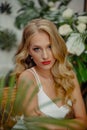 Beautiful young girl with blond hair and a Hollywood wave and with red lipstick on her lips in a white evening dress in the floor Royalty Free Stock Photo