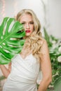 Beautiful young girl with blond hair and a Hollywood wave and with red lipstick on her lips in a white evening dress in the floor