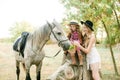 Beautiful young girl with blond hair in a suede jacket with fringe with little sister in a straw hat and checkered vintage dress Royalty Free Stock Photo