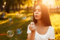 Beautiful young girl blowing soap bubbles in the park at sunset. Royalty Free Stock Photo