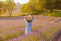 The beautiful young girl in a blue dress and cap walks across the field of a lavender, long curly hair, smile, pleasure