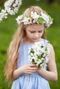 Beautiful young girl in blue dress in the garden with blosoming  apple trees. Cute girl  holding a bouquet of flowers Royalty Free Stock Photo