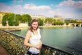 Beautiful young girl on bridge with locks of lovers on river Seine in Paris, bright sunny summer day. Tour of Paris, France Royalty Free Stock Photo