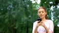 Beautiful young girl chatting on smartphone spending time outdoor, addiction Royalty Free Stock Photo