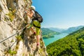 Beautiful young girl climbing Drachenwand via ferrate above scenic Mondsee lake, Austria