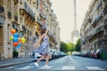Beautiful young girl with colorful balloons running across the street in Paris Royalty Free Stock Photo