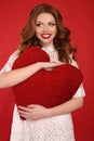 Beautiful young girl with dark hair and bright makeup, in elegant dress holding big red heart in hands Royalty Free Stock Photo