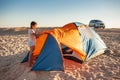 Beautiful young girl with dark hair sets up a tent on the beach