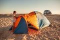 Beautiful young girl with dark hair sets up a tent on the beach