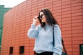 Beautiful young girl with dark hair wearing casual clothes posing near red wall, street style, outdoor portrait, hipster girl in Royalty Free Stock Photo