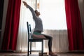 Woman doing exercises at home using chair. Urdhva hastasana asana. Royalty Free Stock Photo