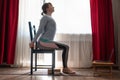 Woman doing exercises at home using chair. Urdhva hastasana asana.