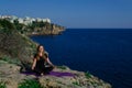 Beautiful young girl doing yoga meditation outdoors on rocks near blue sea Royalty Free Stock Photo