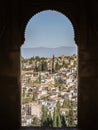 A beautiful young girl in a dress and a hat looking at the Albaicin district of Granada from the window of the Alhambra palace Royalty Free Stock Photo