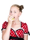 Beautiful young girl dressed in a red dress with white polka dots eating an apple. healthy food - strong teeth concept Royalty Free Stock Photo